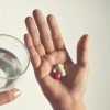 Hands holding pills and a glass of water