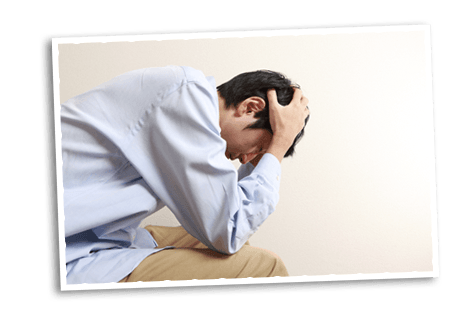 Young man hunched over holding his head