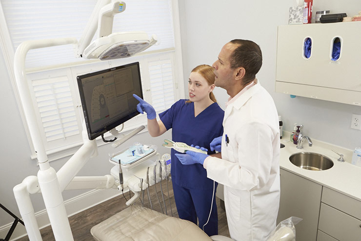 Doctor and technician reviewing patient data on computer screen