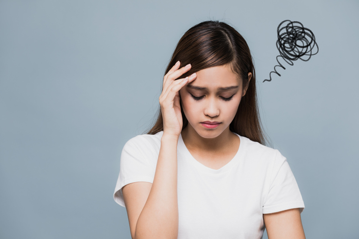 Young girl holding her head with a swirl of black lines coming from one side