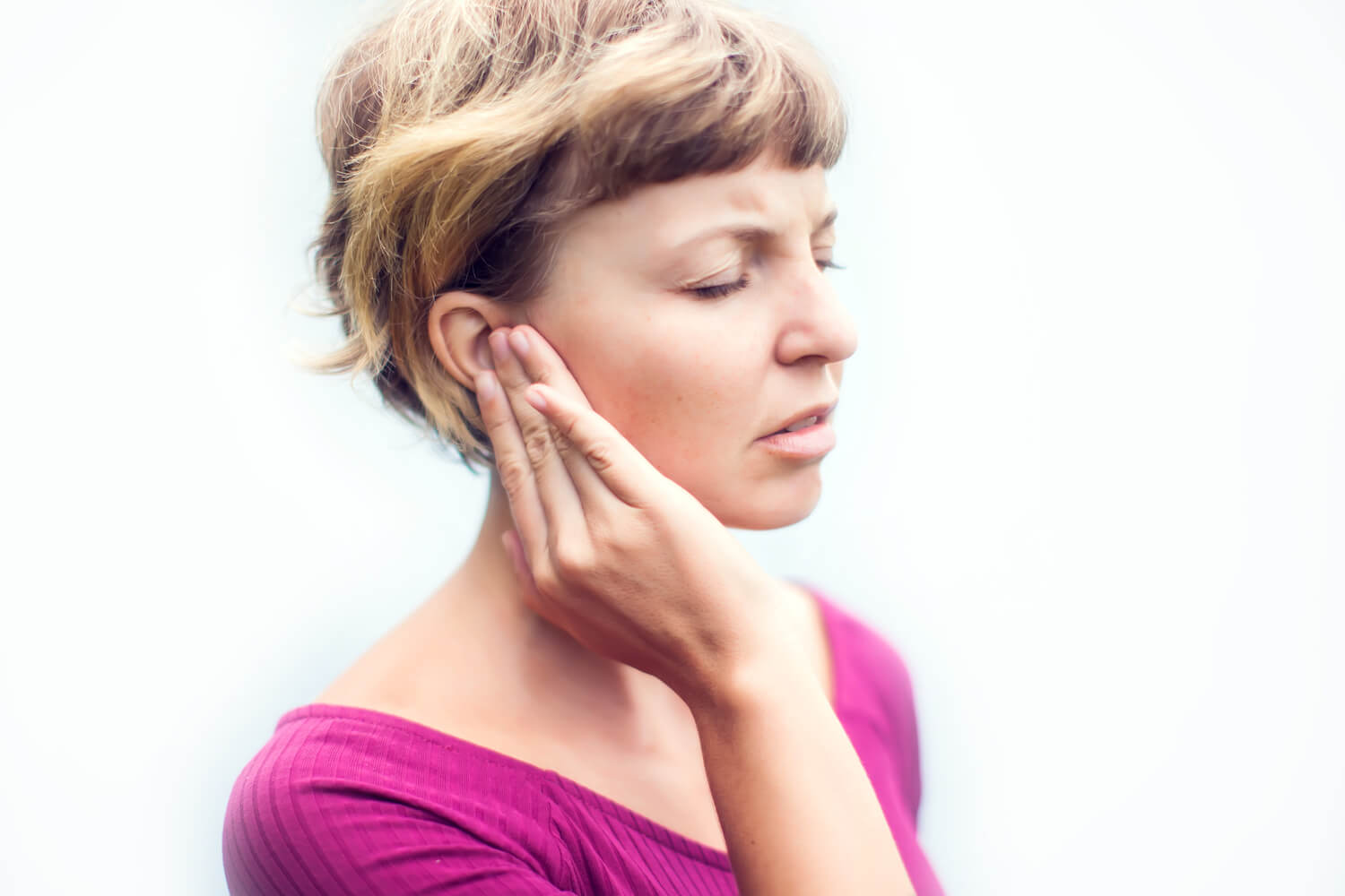 Blonde woman holding her ear