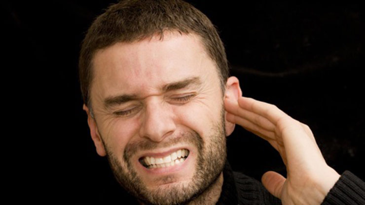 Man holding his ear and wincing in pain