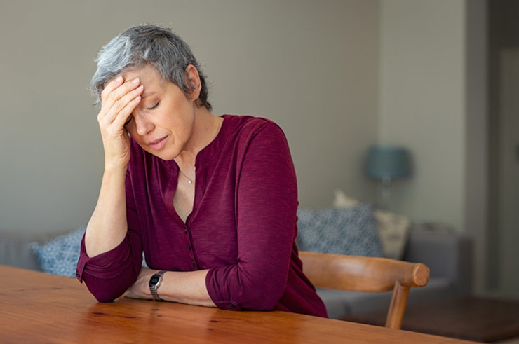 Woman sitting at a table holding her head