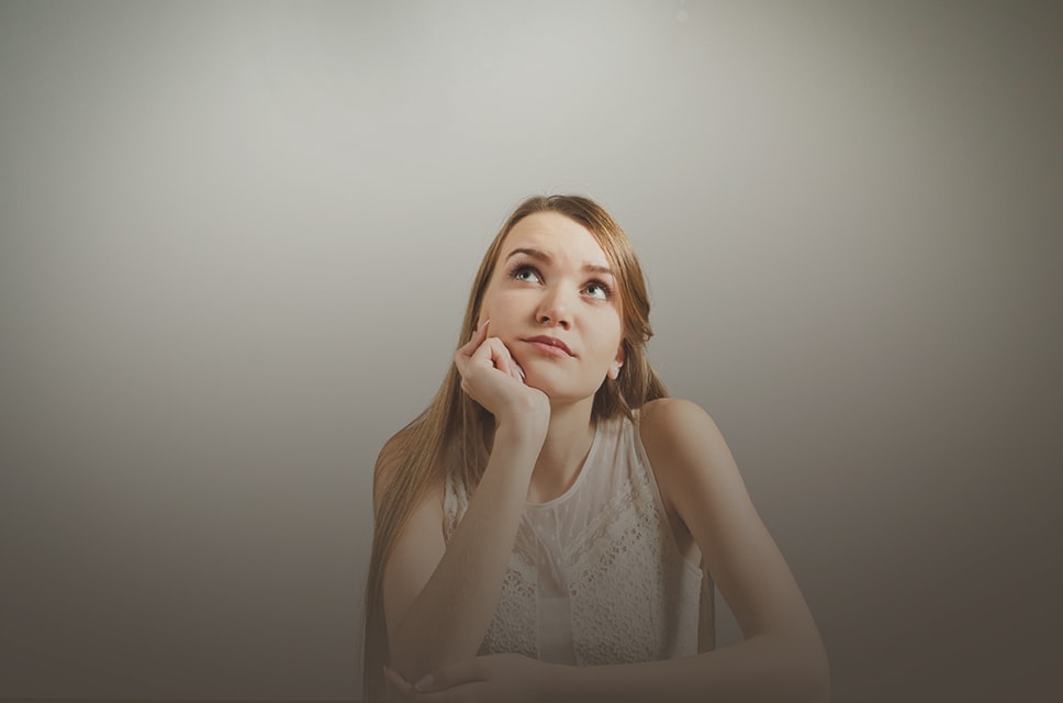 Young woman with her head resting on her hand deep in thought