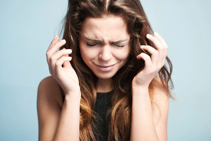 Young woman with long brown hair in severe pain